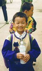 Chinese school boy holds plastic bottle.