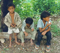 Boys of minority group sit by road side.